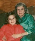 Grandmother and granddaughter sitting on t he couch in robes.